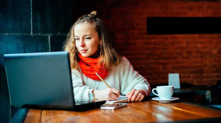 Mujer trabajando desde casa con una computadora y un café en la mesa Mujer trabajando desde casa con una computadora y un café en la mesa