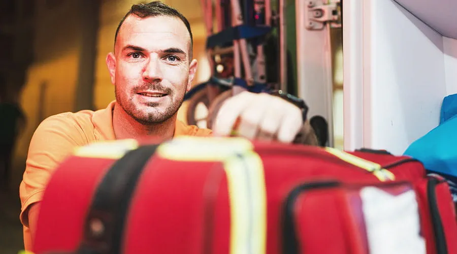 Repartidor sosteniendo una bolsa médica roja en interiores Repartidor sosteniendo una bolsa médica roja en interiores