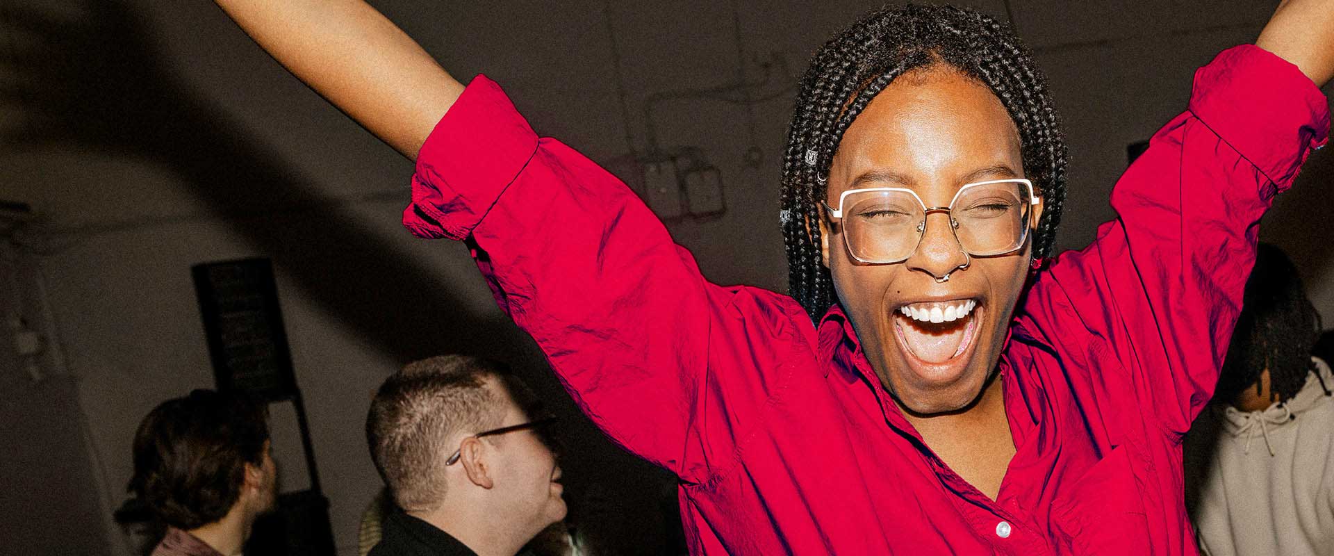 Person celebrating with raised arms in social setting Person celebrating with raised arms in social setting