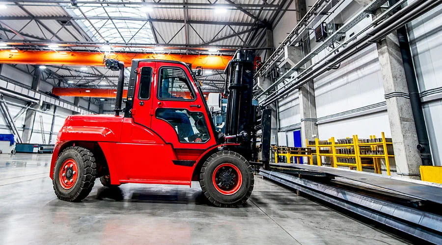 Red forklift operating inside warehouse environment Red forklift operating inside warehouse environment