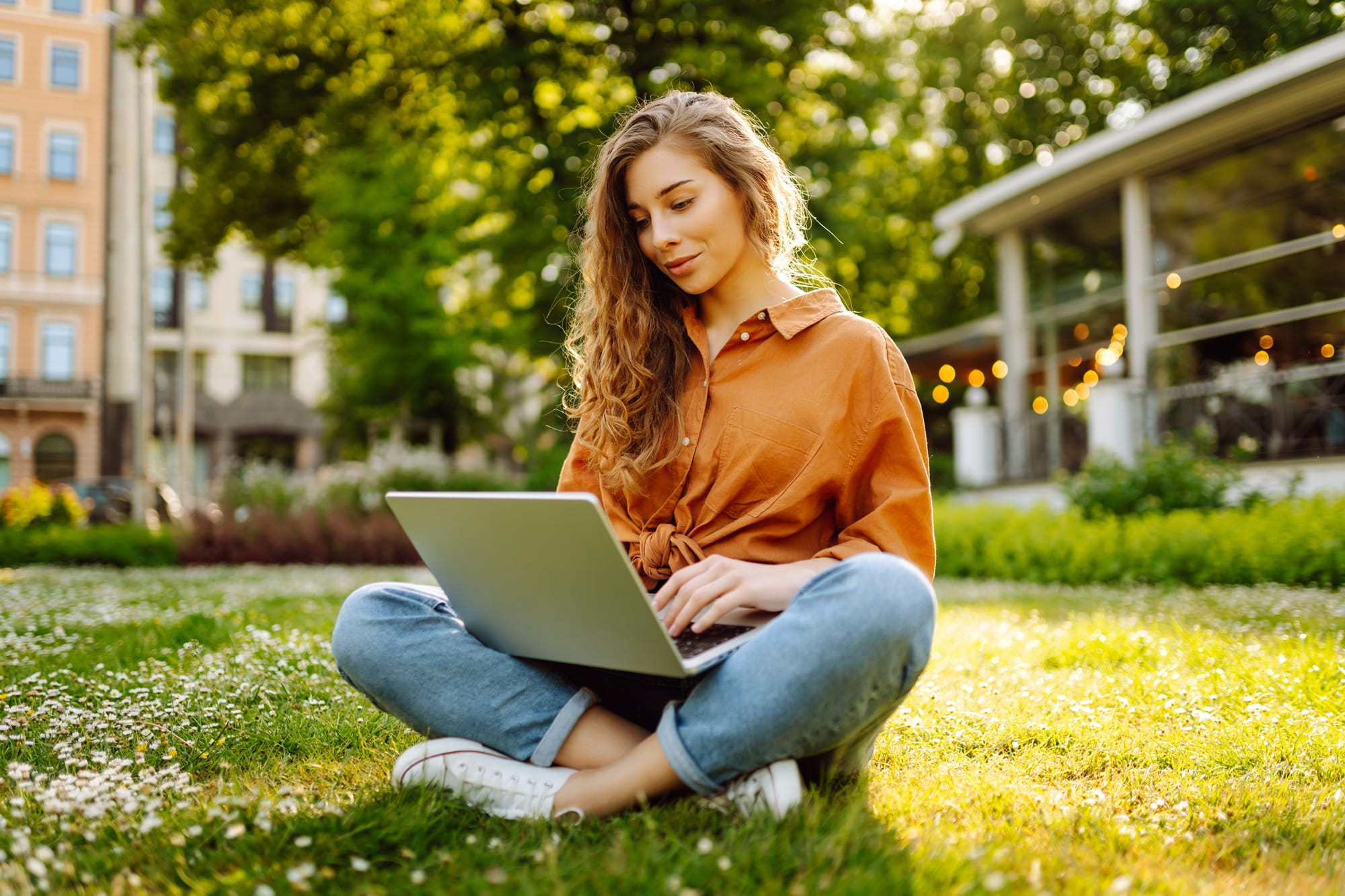 Woman sitting on the ground in a park with a laptop on her lap. Woman sitting on the ground in a park with a laptop on her lap.
