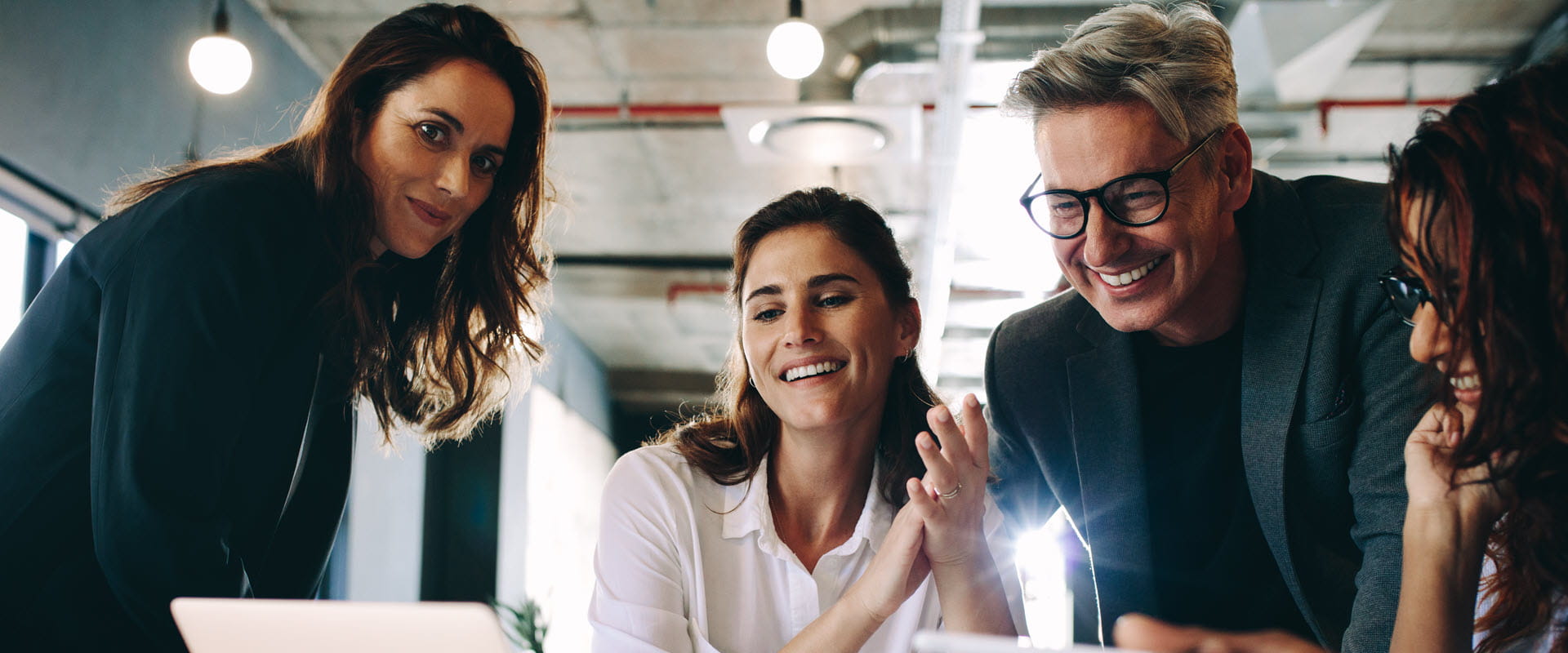 group of smiling professional people looking at laptop group of smiling professional people looking at laptop